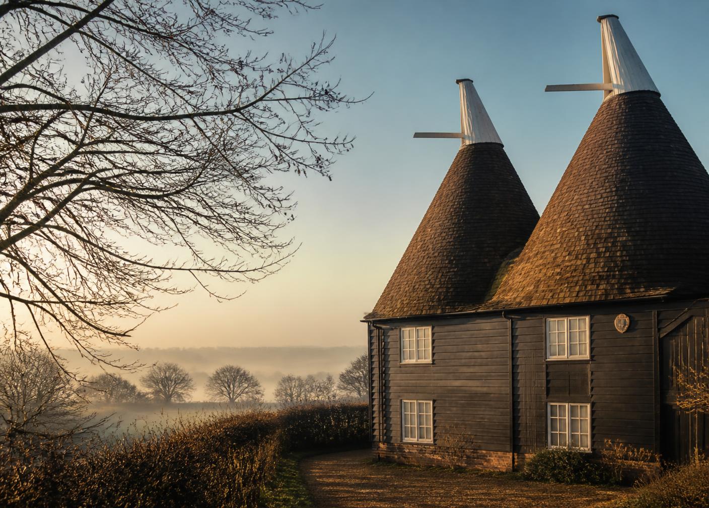 A traditional Kentish oast house at sunrise with mist across the Medway valley