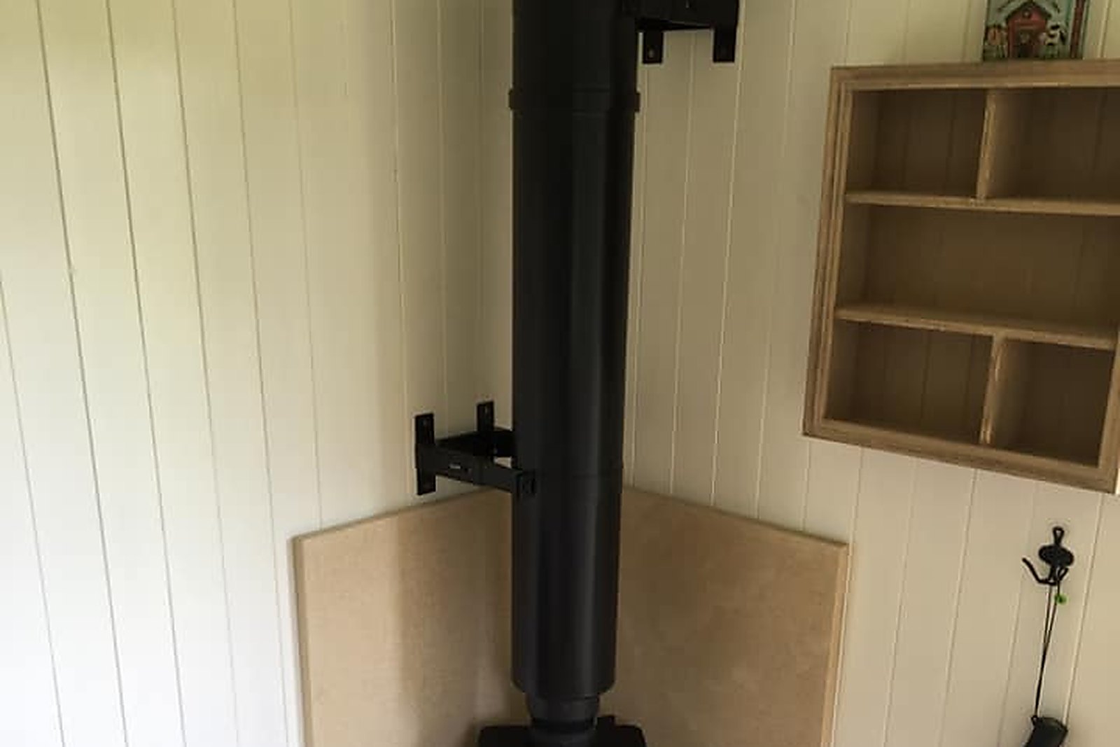 A shepherd hut in Kent with a twin wall flue rising through the roof from a small log burner inside